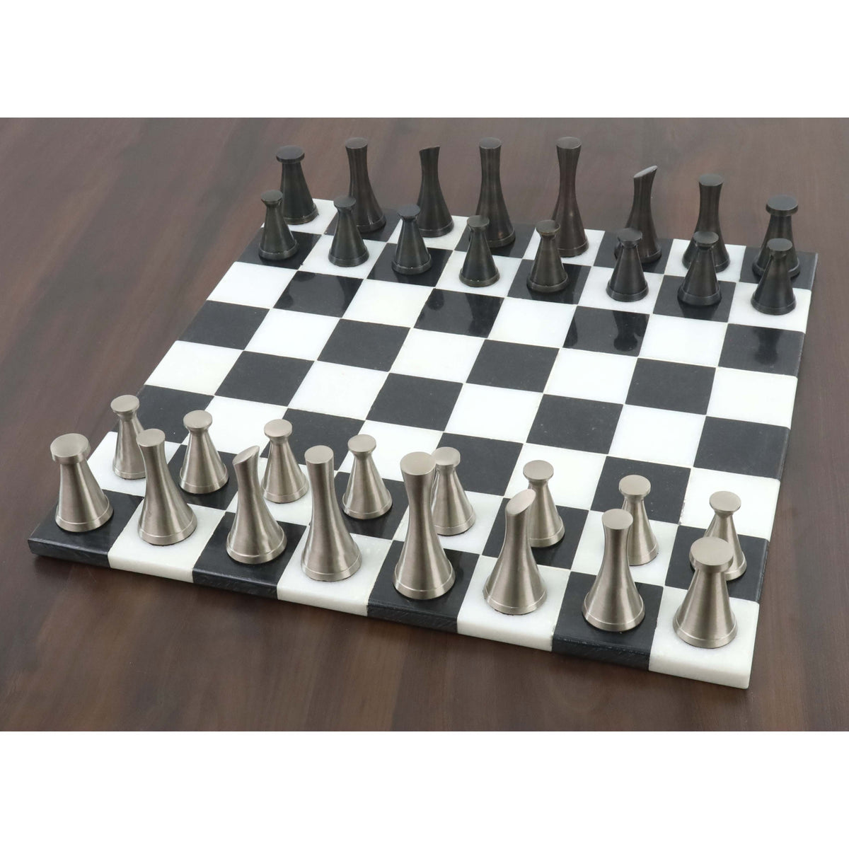3.1" Tower Series brass metal chess pieces arranged on a black and white marble chessboard.