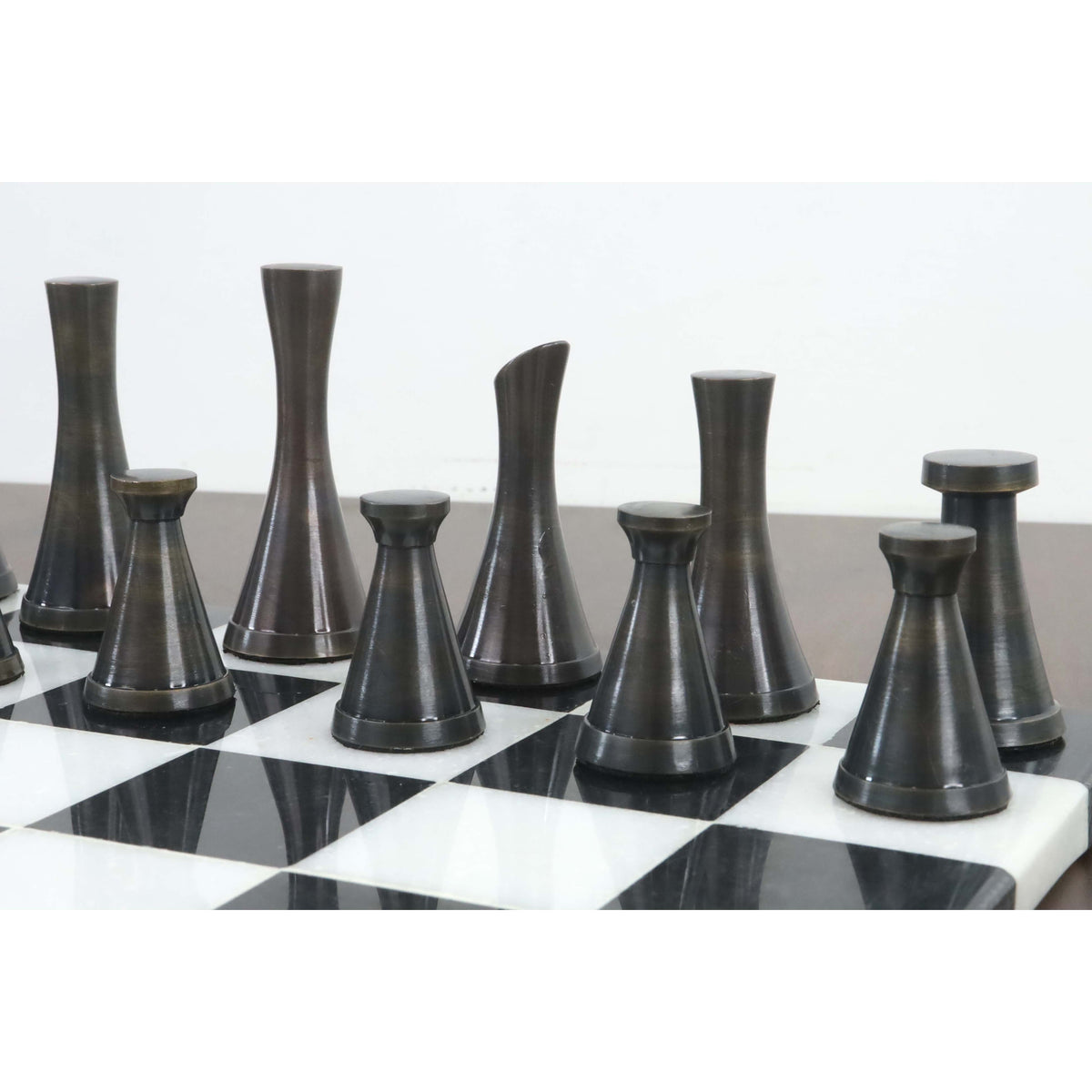 Side profile of the 3.1" Tower Series black brass chess pieces on a marble board.
