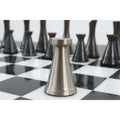 Macro view of a sleek 3.1" Tower Series silver brass chess piece on a marble board.