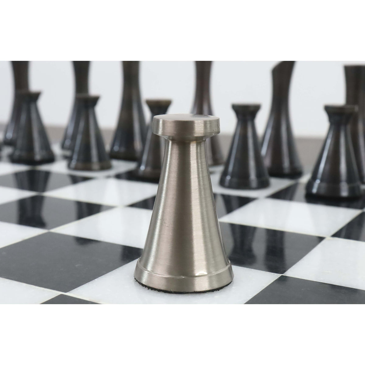 Macro view of a sleek 3.1" Tower Series silver brass chess piece on a marble board.