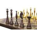 Close-up of antique copper brass chess pieces on a detailed floral engraved metal chessboard.