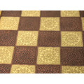 Macro detail of the hand-engraved floral patterns on the squares of a luxury brass metal chessboard.