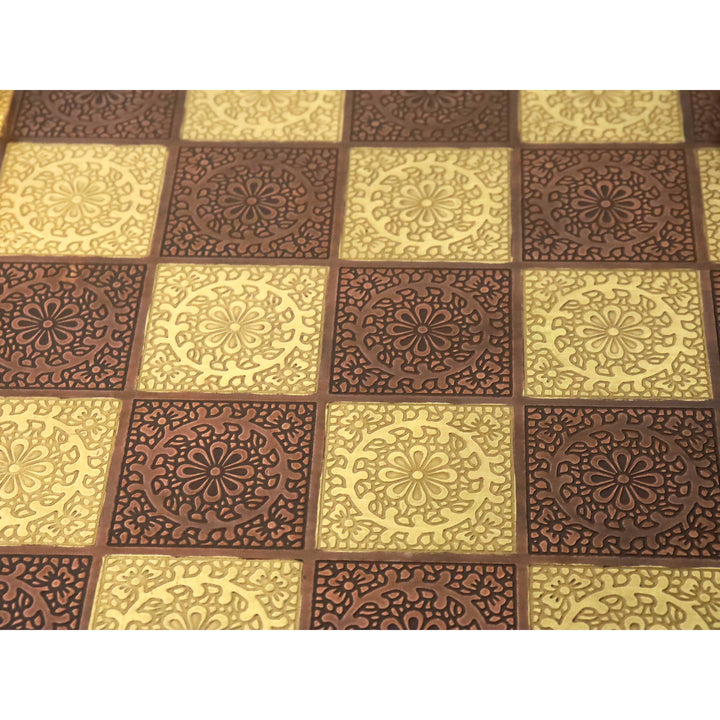 Macro detail of the hand-engraved floral patterns on the squares of a luxury brass metal chessboard.