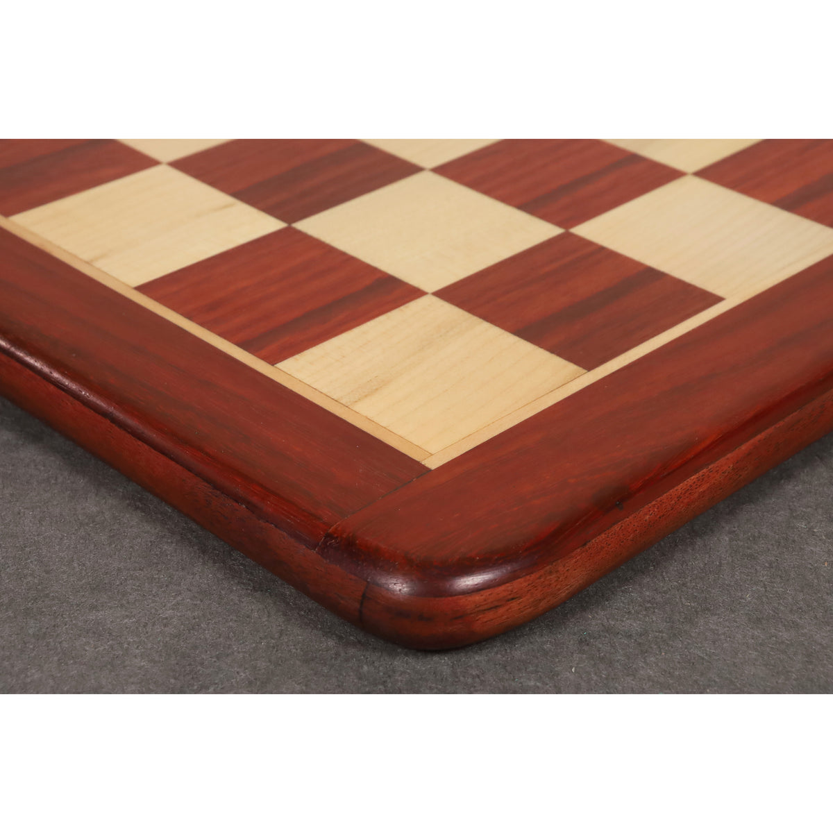 Detailed view of the smooth rounded corner and polished finish of a bud rosewood chess board.