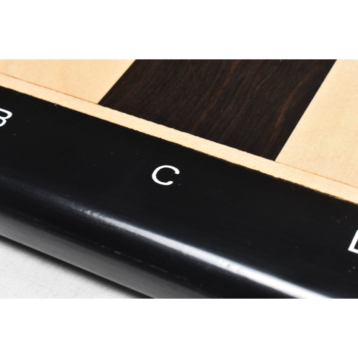 Macro view of a crisp white algebraic letter 'C' engraved on the polished ebony chess board border.