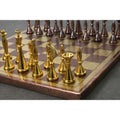 Polished gold brass chess pieces in focus with antique copper pieces blurred in the background.