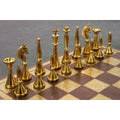 Elegant polished gold brass chess pieces standing on a decorative metal board with floral patterns.