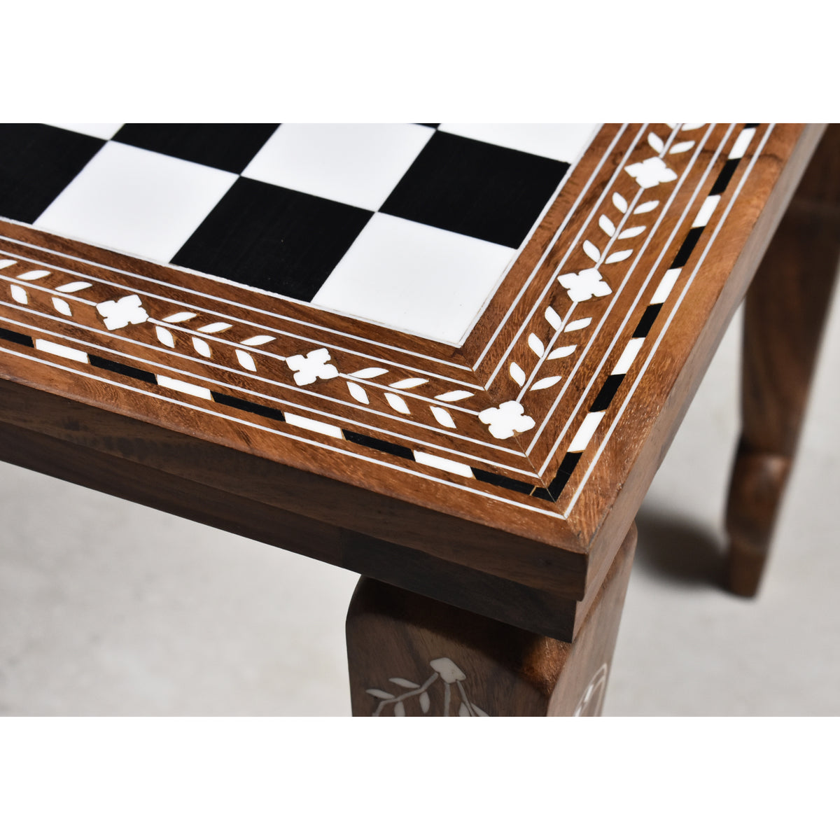 Close-up of the intricate floral leaf inlay on a golden rosewood and acrylic ivory chess board.