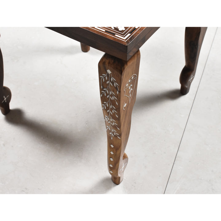 Detailed view of the hand-carved leg with white floral inlay on a library series chess table.