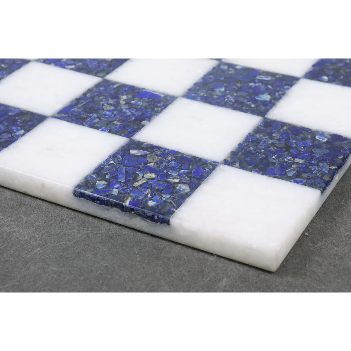Close-up of crushed lapis lazuli stone texture on a handcrafted marble chess board.