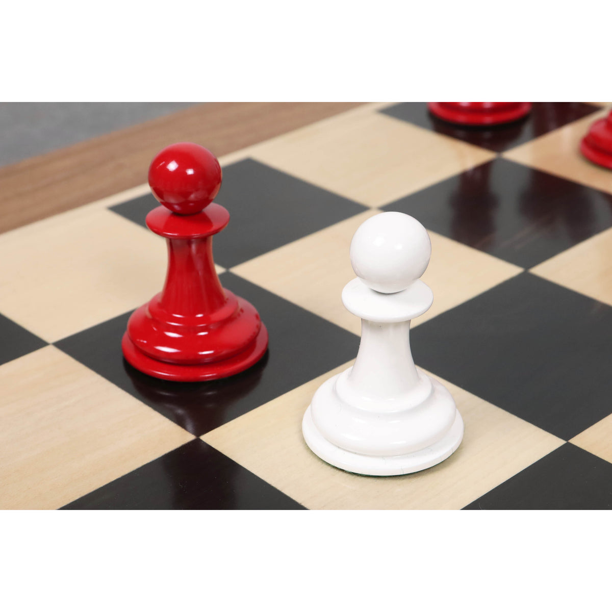 Crimson and ivory lacquer pawns positioned on a wooden chessboard, showing the high-gloss finish.