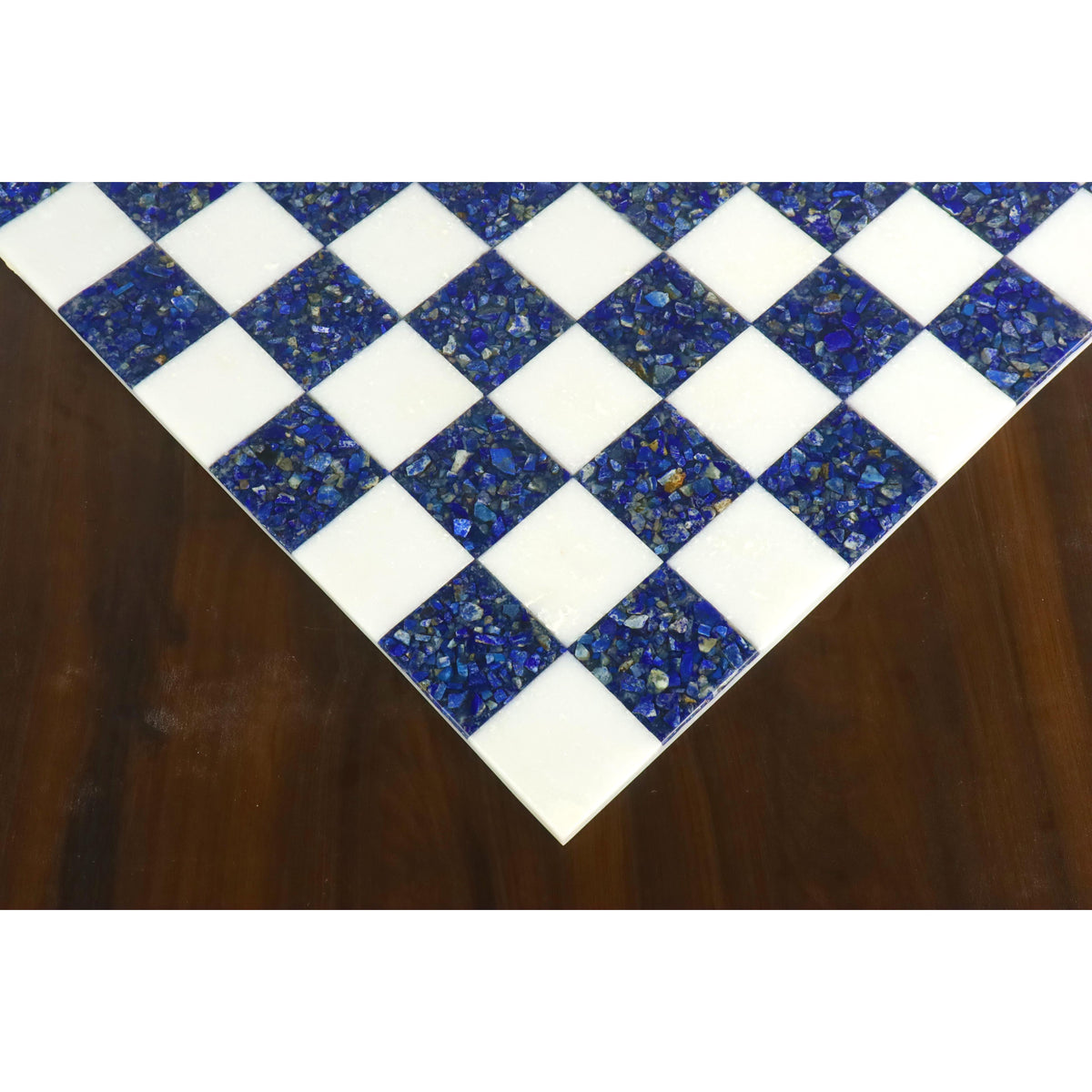 Close-up of the corner of a luxury lapis lazuli and white marble chess board on a wooden table.