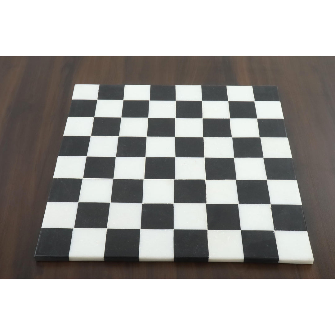 Overhead view of a luxury solid black and white stone marble chess board on a wooden table.