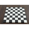 Overhead view of a luxury solid black and white stone marble chess board on a wooden table.