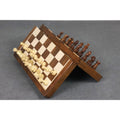 Magnetic chess pieces adhering to a slanted golden rosewood board to show travel stability.