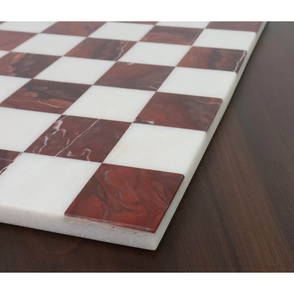 Close-up of maroon semi-precious stone inlay on a marble chess board showing natural white veining.